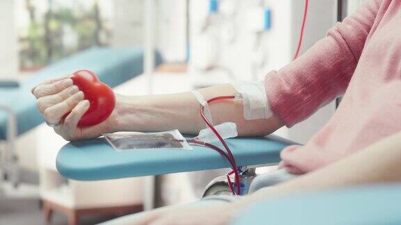 女性献血者的手的特写镜头白人妇女挤压心形红球将血液通过管道泵入袋中捐赠给心脏手术患者