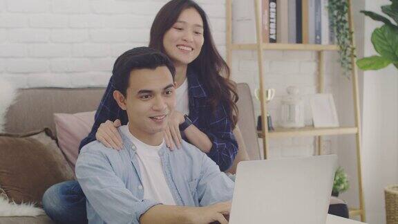 年轻的亚洲情侣情侣对着笔记本电脑上的摄像头一起视频通话在一个房间在家里的背景4k慢动作
