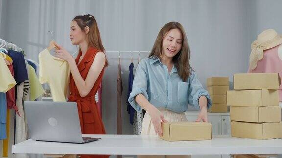 亚洲两位美女为客户打包订购的衣服装箱年轻有吸引力的商业人士工作准备包裹盒检查电子商务航运在线零售在仓库商店出售