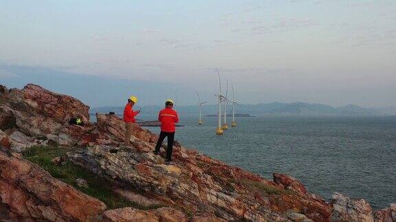黎明时分技术人员使用无人机检查风力发电厂的涡轮机