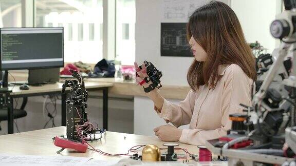 年轻的创新工程师在实验室测试创新机器人技术年轻的亚洲女性为机械机械手创造运动有技术或创新观念的人