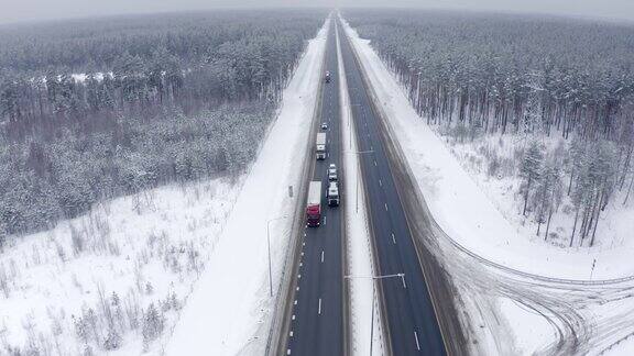 几辆卡车正沿着被雪覆盖的树木之间的道路运输货物