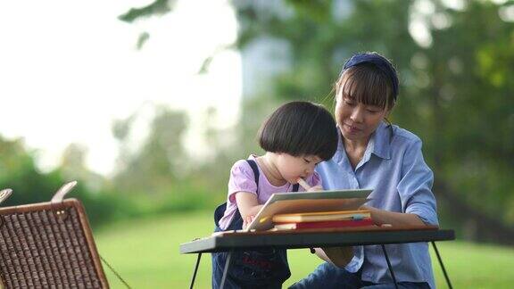 亚洲小女孩与年轻的妈妈在花园里学习击掌成功