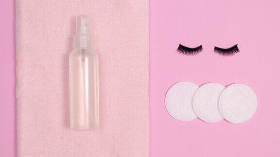用卸妆水在粉红色的背景上眨着睫毛平放止动