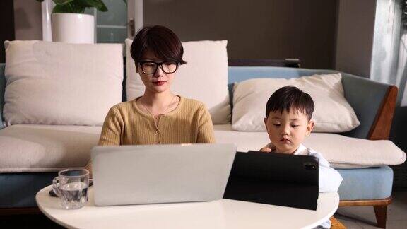 母亲在家工作儿子一起用平板电脑