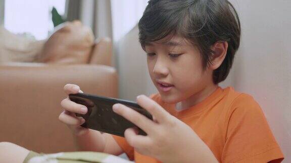 亚洲男孩沉迷于智能手机游戏上网退出了亚洲男孩手玩智能手机游戏在家里的沙发上呆在家里的想法概念