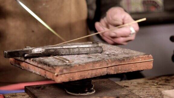 一位珠宝工匠在他的工作室里制作一只手镯
