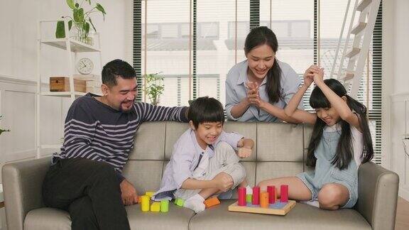 幸福的亚洲家庭父母和孩子一起在沙发上玩五颜六色的玩具