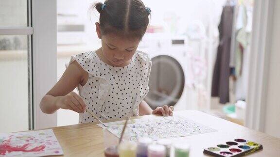 开朗的女孩在家里用画笔画水彩画