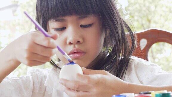 复活节期间一名亚洲女孩正兴高采烈地在彩蛋上画画