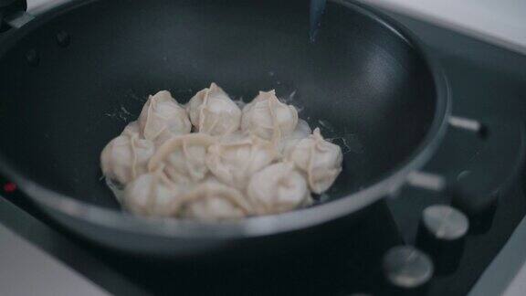 近距离的中国奶奶准备煮蒸汽中国饺子在煮锅在itchen