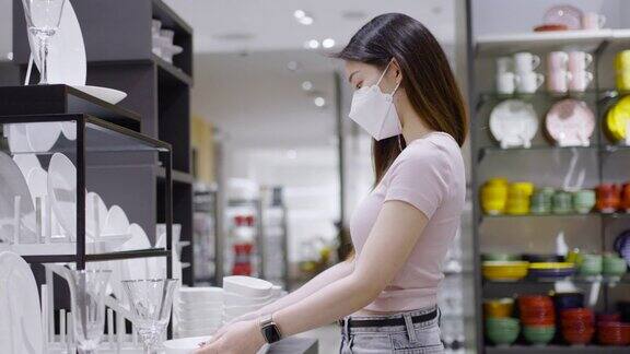 亚洲妇女戴着口罩在零售商店挑选厨房用具