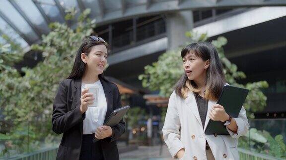两个放松的商务女性在休息时间漫步在现代工作场所一起享受谈话