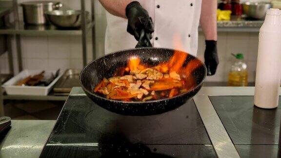 厨师在餐厅的厨房炉子上用煎锅用火焰烹饪