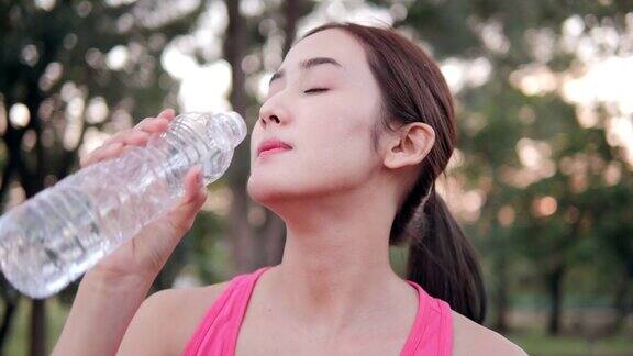 年轻美丽的亚洲女人在公园休息女人运动完喝水具有保健、运动和锻炼理念的人