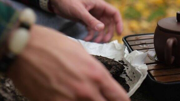 特写镜头男性双手将压好的普洱茶包在纸上户外茶道