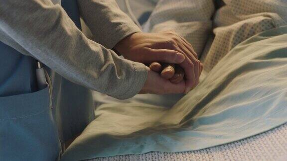 护士在病床上牵着老人的手表达对病愈老人的关爱