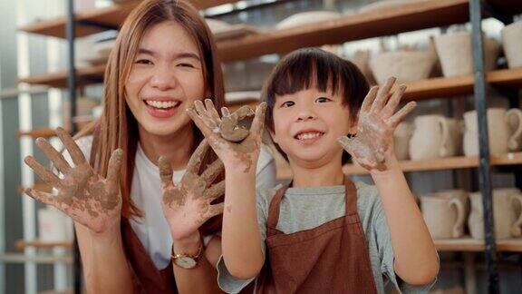 美丽的陶工教她的儿子制作环保陶器的肖像