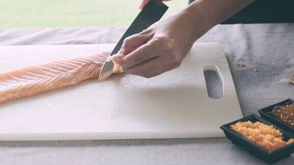 特写的女人切小块的鲑鱼为寿司准备