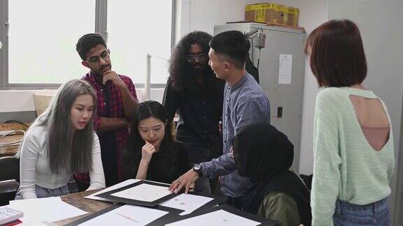 亚裔马来男教师反馈检查他的学生珠宝设计工作在大学教室