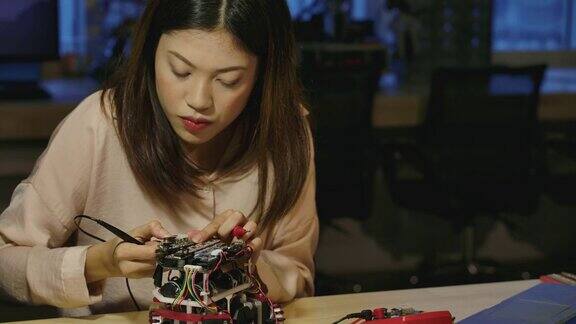 年轻的亚洲女性电子开发工程师与机器人一起工作在车间测量机器人原型电路中的信号有技术或创新观念的人