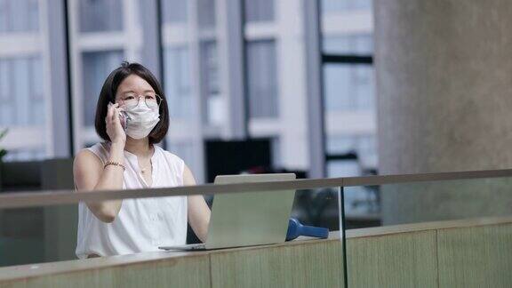 亚洲商界女性在干净现代、没有新冠肺炎的办公室里戴口罩保持社交距离利用高速互联网技术在线工作视频会议