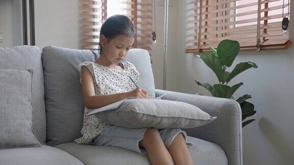 专心致志的女孩坐在沙发上画画和学习