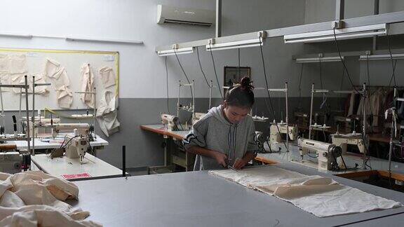 亚洲华裔时装女大学生在大学工作坊裁剪面料做服装项目