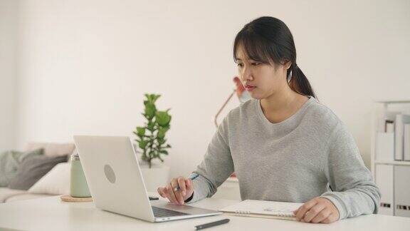 亚洲十几岁的女孩早上在家里用笔记本电脑在纸上画画、素描