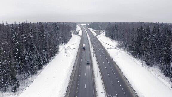冬天积雪覆盖的森林里道路上来往的汽车