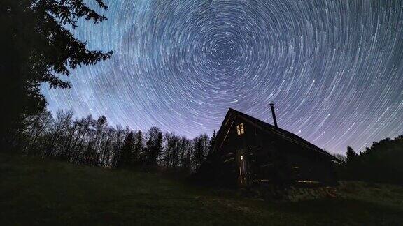 星际轨迹银河系的恒星轨迹在夜空森林自然中古老的木屋上旋转