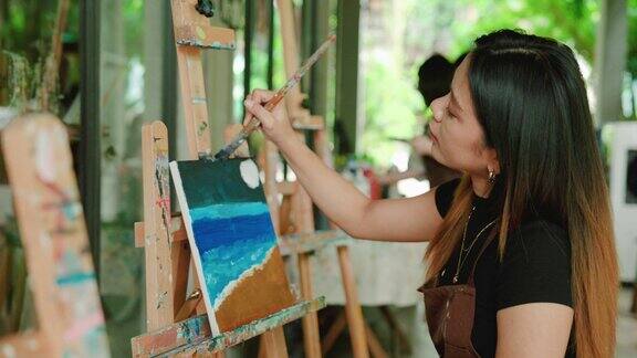 年轻的亚洲女子在艺术工作室给沙滩画上色