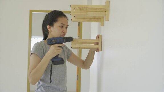 一个女人正在房子的墙上安装一个木架