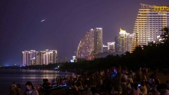 夜光照耀三亚拥挤的海滩海岸线酒店全景4k时间推移海南岛中国