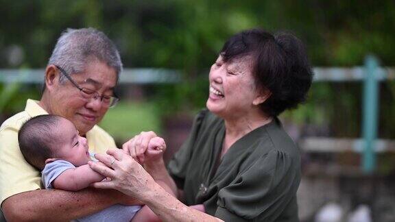 一对亚洲华人老夫妇和他们的孙子在自家前院玩