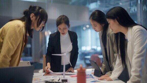 一位亚洲女商人在办公室的桌子上和同事们谈话