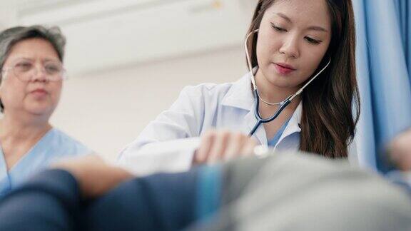 亚洲年轻女医生用听诊器给一名老年男子做体检的特写镜头