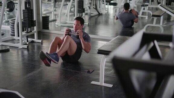 在健身房里用哑铃坐起来锻炼腹部肌肉的人