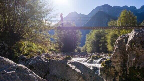 一名年轻女子正穿过山间溪流上的吊桥