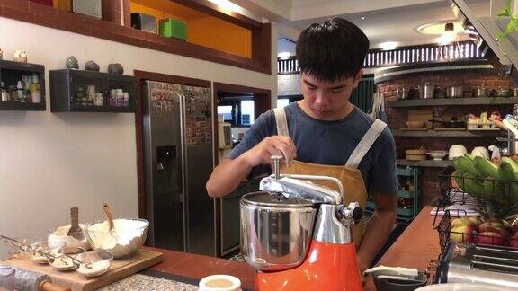 亚洲华人面包师少年在厨房的搅拌机里加入面粉