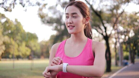 Smartwatch运动亚洲女人使用智能手表在公园女性手表触屏进入手表应用