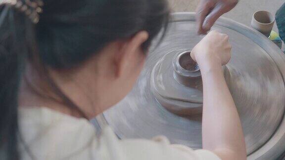 亚洲妇女粘土艺术家在她的工作室与纺纱陶轮工作可持续性的生活方式