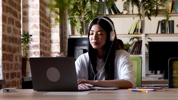 一个亚洲女孩在网上学习在笔记本电脑上通过视频电话与同伴交流