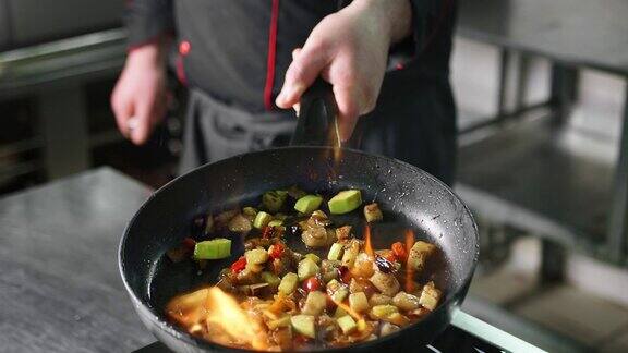厨师用平底锅在燃烧的火上慢动作烹调蔬菜近距离拍摄4k红色相机