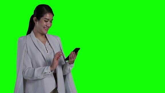 女商人的肖像穿着聪明的西装和持有智能手机数字与孤立的绿色屏幕背景或色度键