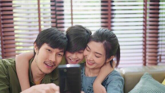 幸福快乐的家庭爱亚洲家庭节日活动爸爸拿着智能手机在一起自拍的妈妈儿子和爸爸在客厅的家庭内部背景