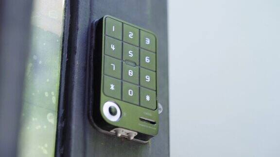 一只手按下公寓电子门锁键盘上的安全码进入
