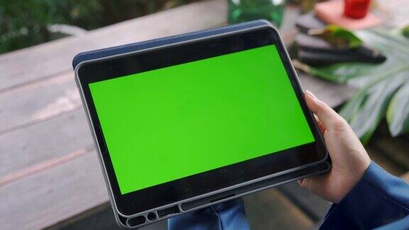 一个女人手里拿着一个有绿色屏幕的平板电脑的特写