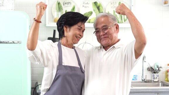 年长的亚洲夫妇在厨房做饭70多岁的老人和女人一起在厨房柜台上准备食材