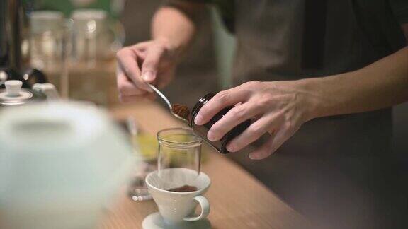 亚洲华人高级男咖啡师加入舀烤碎咖啡准备冷煮冰滴咖啡在咖啡店